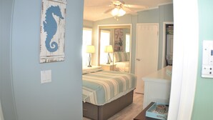 Une chambre à coucher avec un lit, des lampes de chevet, un ventilateur de plafond et une décoration murale représentant un hippocampe.