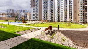 A residential area with high-rise apartment buildings, a playground, and a well-maintained garden. - Nova Letnica Apartment (Gdansk)