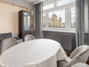 Una habitación con una mesa de comedor, sillas, un sofá y un ventanal con vistas a un edificio histórico.
