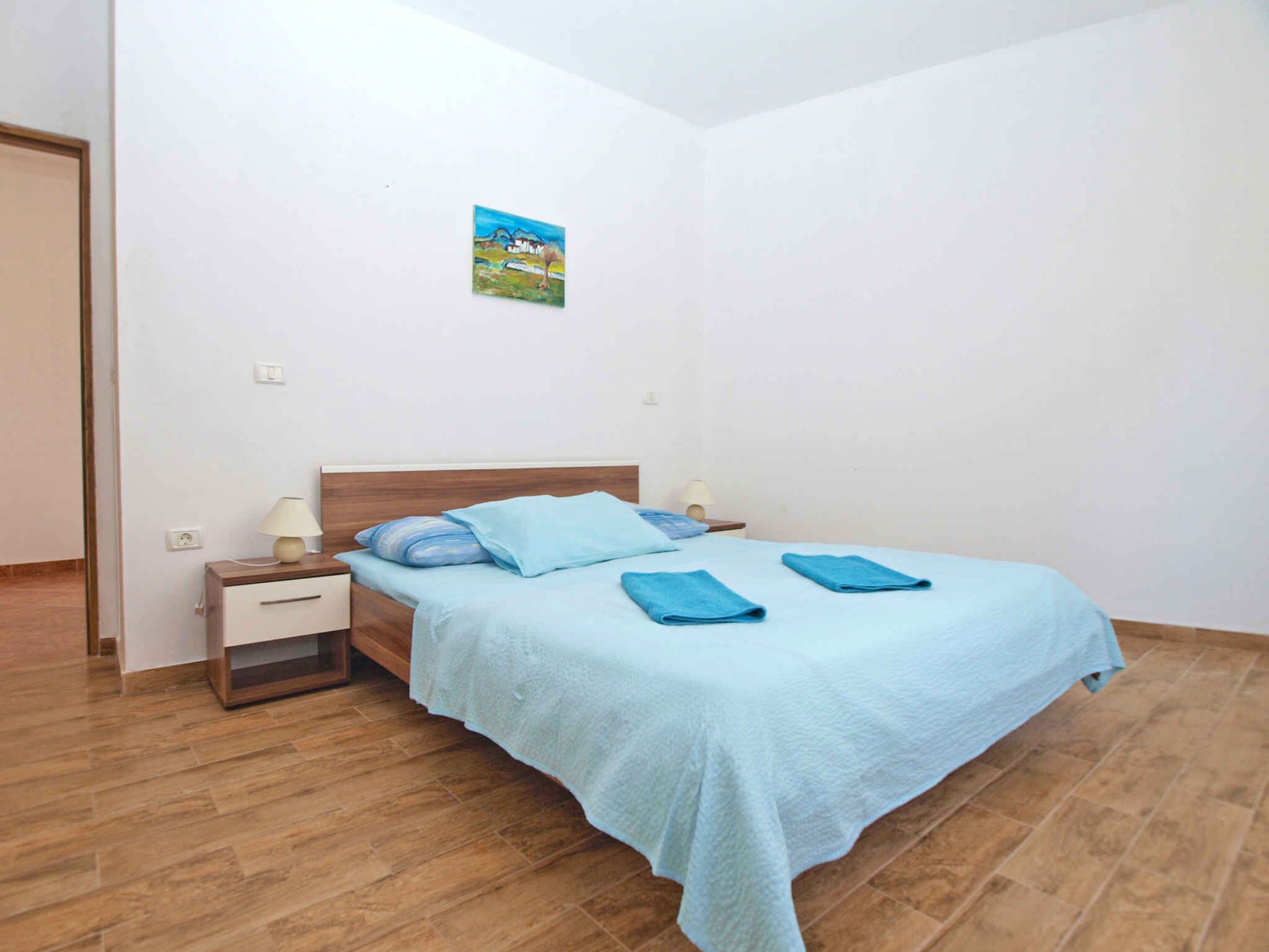 A bedroom with a wooden bed, a nightstand, a lamp, and a painting on the wall.
