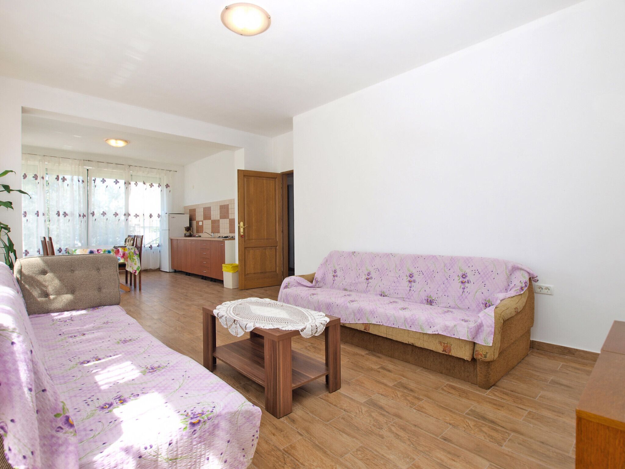 A living room with a sofa, a small table, and a kitchen in the background.