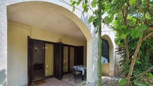 A covered outdoor area with a table and chairs, a door leading inside, and a stone-tiled floor. - Holiday apartment mit Terrasse (Valbandon)