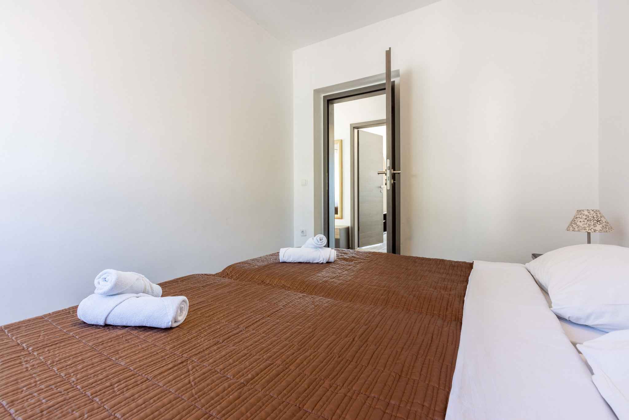 A hotel room with two beds, a door, and a lamp.