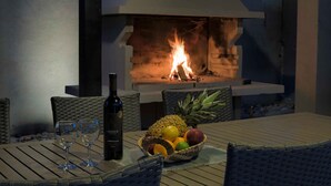 Un coin repas avec une table dressée pour deux personnes, une bouteille de vin et un panier de fruits.