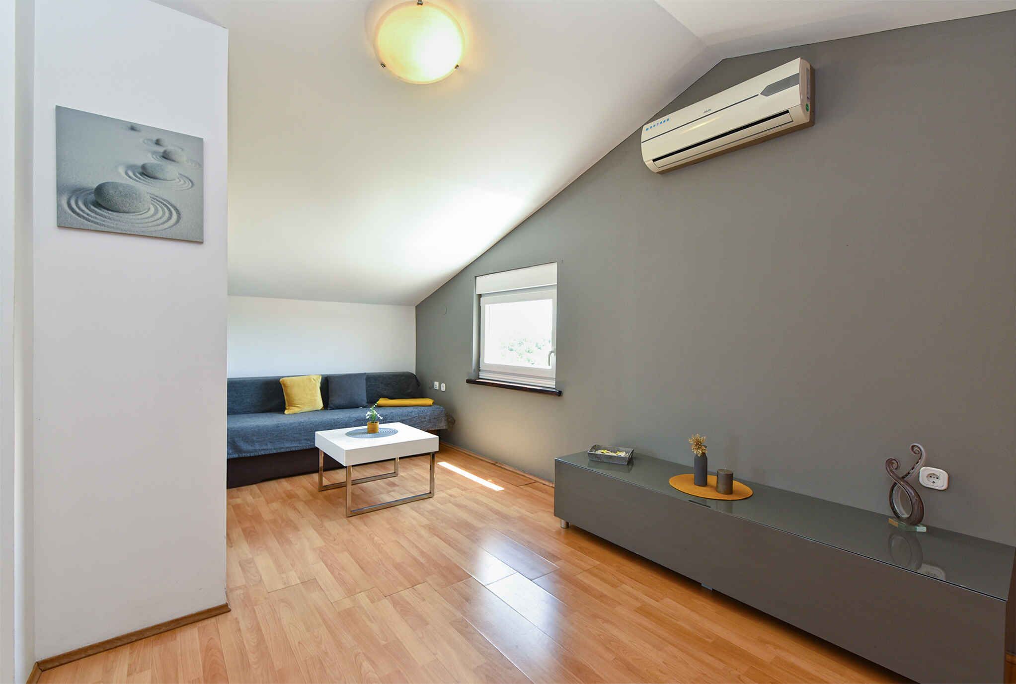 A modern living room with a wooden floor, grey sofa, and a white coffee table.