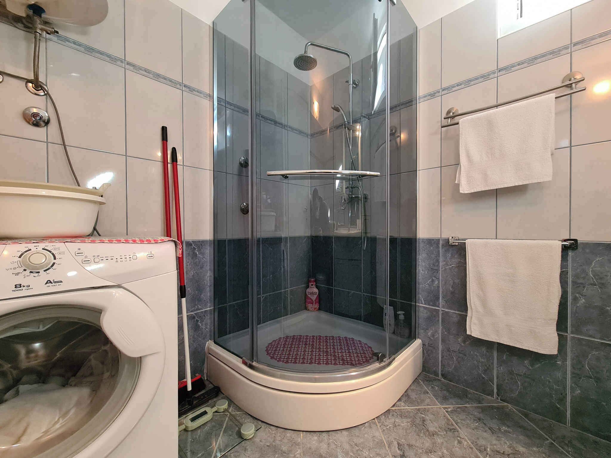 Une salle de bain moderne avec une douche à parois de verre, un lave-linge et un porte-serviettes.