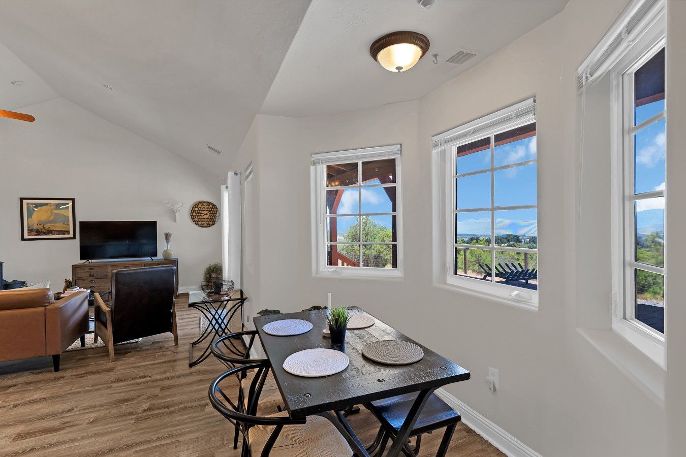 A spacious living area with a dining table, chairs, a television, and a view of the outdoors.