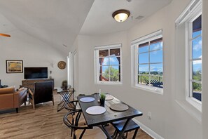 Un espacio habitable amplio con una mesa de comedor, sillas, un televisor y vistas al exterior.