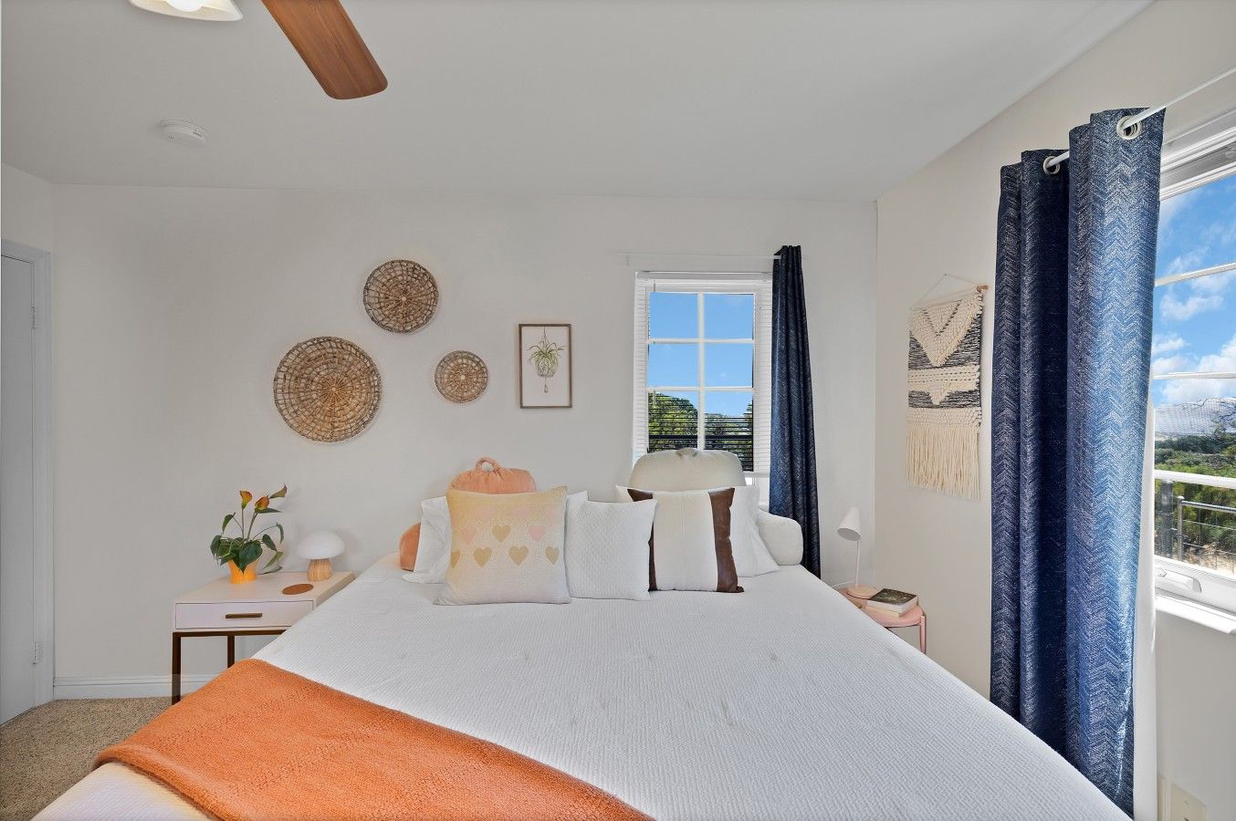 A bedroom with a bed, bedside tables, a window with curtains, and wall decorations.
