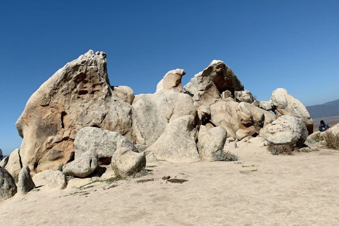 A desert landscape with large boulders and a clear blue sky.