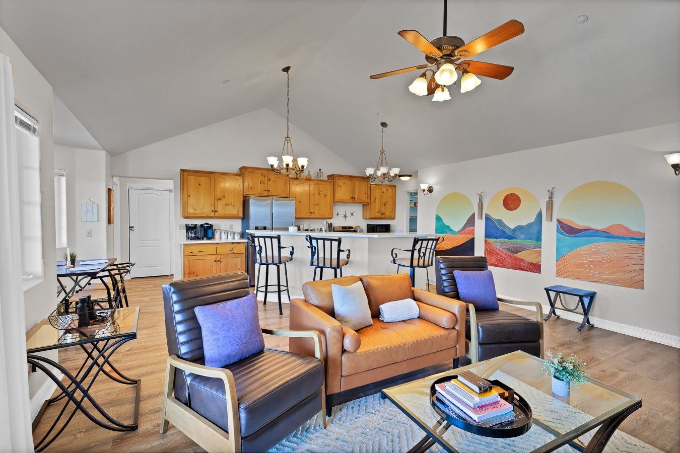 A spacious living area with a sofa, chairs, a dining table, and a kitchen in the background.
