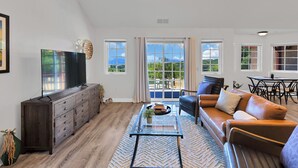 A living room with a TV, a sofa, a coffee table, and a dining area with a table and chairs.