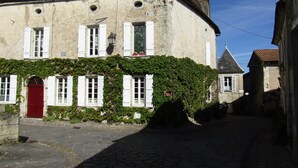 Un bâtiment historique avec une porte rouge, des volets blancs et une enseigne indiquant qu’il s’agit d’un hôtel.