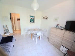 Una sala de estar con una mesa de comedor, sillas, un sofá, un televisor y un mueble aparador.