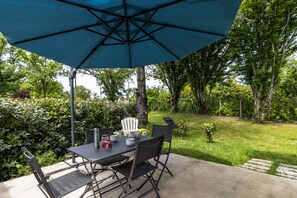 An outdoor patio with a table, chairs, and a large umbrella.