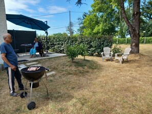 A backyard with a barbecue grill, outdoor seating, and a covered patio area.