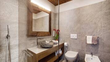 Un bagno moderno con un mobile bagno in legno, uno specchio grande, un lavabo in pietra, un water e un bidet.