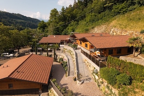 A hillside property with terraced houses, a paved driveway, and a stone retaining wall.