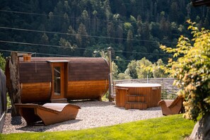 Une cabane en bois avec une porte, un jacuzzi et un bateau en bois, le tout situé sur un chemin de gravier.