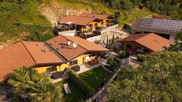 Il s’agit d’une propriété résidentielle comprenant plusieurs maisons, chacune dotée d’un toit en tuiles, d’espaces extérieurs aménagés et de panneaux solaires.