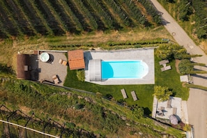 An aerial view of a property with a swimming pool, outdoor seating, and a patio area.