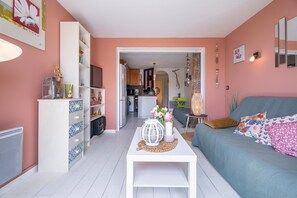 A living room with a sofa, a white coffee table, and a kitchen in the background.