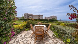 A patio with a round table and chairs, a stone pathway, and a view of buildings in the background. - Magnificent T2 Apartment with Sea View and Wi-Fi (Six-Fours-les-Plages)