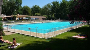 A rectangular swimming pool with a fenced deck, surrounded by grass and trees. - Magnificent T2 Apartment with Sea View and Wi-Fi (Six-Fours-les-Plages)