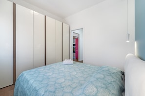 A bedroom with a bed, a wardrobe, and a door leading to another room. - Apartment '4 Seasons' with Balcony, Wi-Fi and Air Conditioning (Guspini)