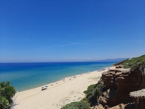 A beach with clear blue water, sandy shore, and rocky cliffs. - Apartment '4 Seasons' with Balcony, Wi-Fi and Air Conditioning (Guspini)
