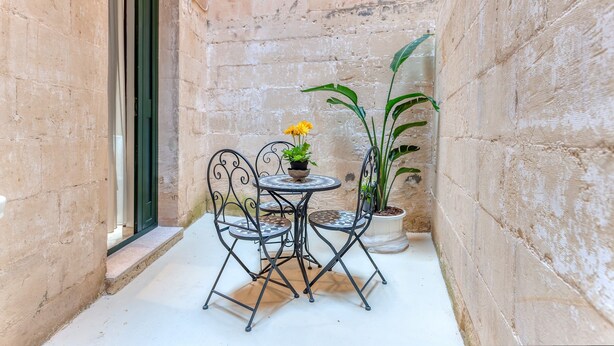 A small outdoor patio with a round table and two chairs, a potted plant with yellow flowers, and a potted plant with green leaves. - Apartment 'Nest 27' with Private Terrace, Wi-Fi and Air Conditioning (Lecce)