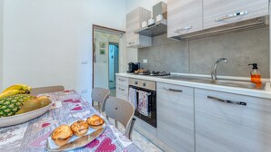A modern kitchen with a dining table set for two, a refrigerator, stove, and a sink. - Apartment 'Nest 27' with Private Terrace, Wi-Fi and Air Conditioning (Lecce)