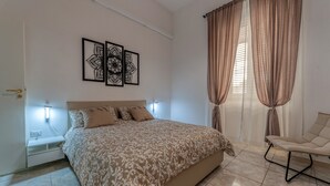 A bedroom with a bed, bedside lamps, a chair, and a wall-mounted artwork. - Apartment 'Nest 27' with Private Terrace, Wi-Fi and Air Conditioning (Lecce)