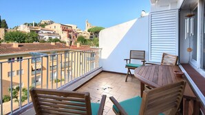 Ein Balkon mit Tisch und Stühlen, mit Blick auf eine Stadtlandschaft mit Gebäuden und einer Kirche.