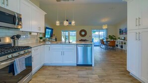 A modern kitchen with white cabinets, stainless steel appliances, and a central island. - New! Resort Style Oasis ~ Heated Pool & Game Room (Minneola)