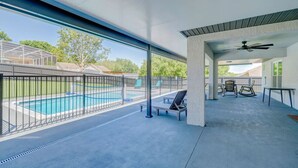 A covered outdoor area with a pool, seating, and a ceiling fan. - New! Resort Style Oasis ~ Heated Pool & Game Room (Minneola)