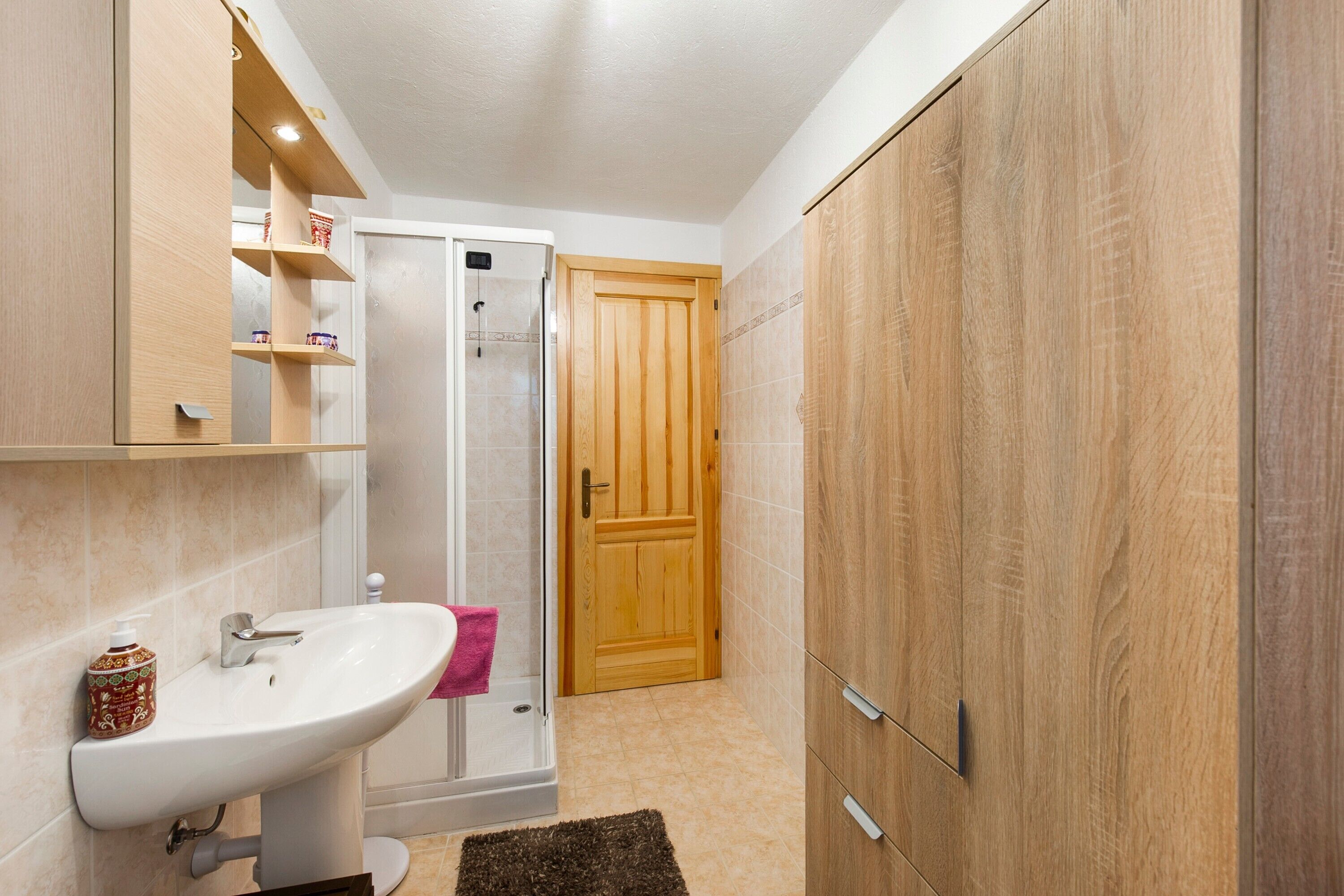 Ein Badezimmer mit Waschbecken, Dusche und Holzschränken.
