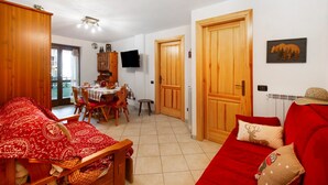 Un salon chaleureux avec un canapé rouge, une table à manger en bois et un téléviseur fixé au mur.
