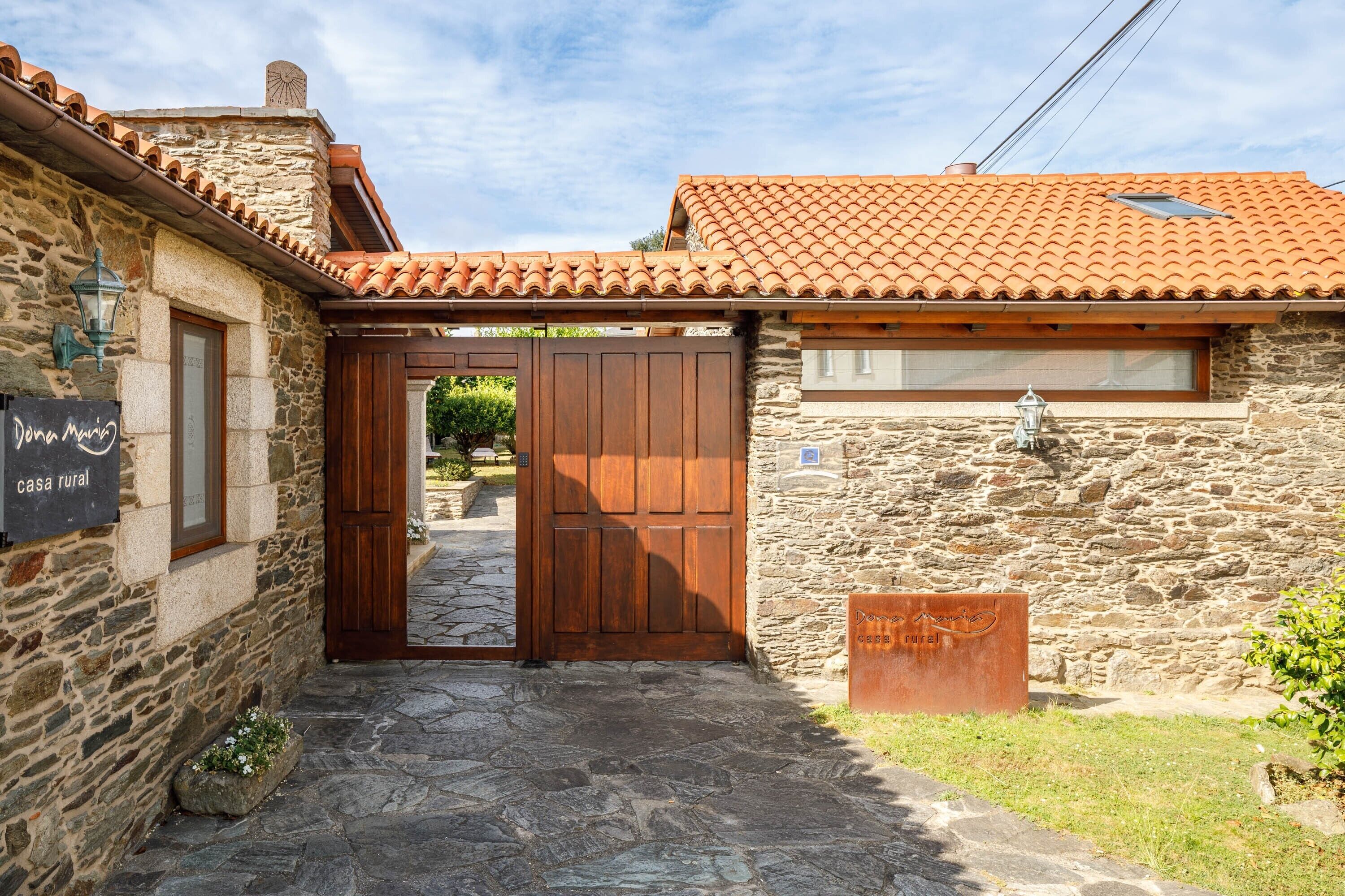 A rustic stone building with a tiled roof, a wooden door, and a sign indicating it's a rural house.
