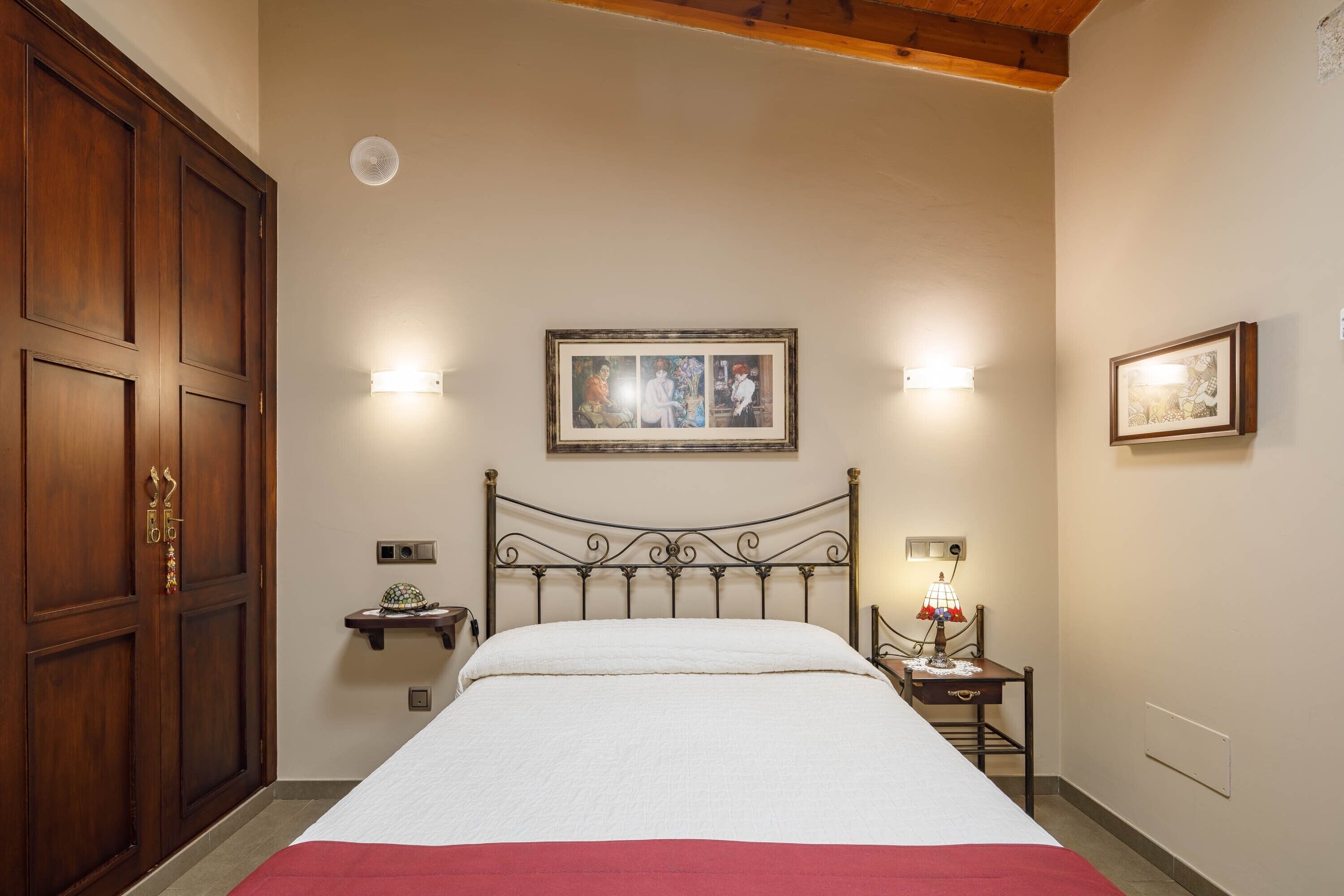 Una camera da letto con un letto grande, un armadio in legno, un comodino con una lampada e un quadro appeso al muro.