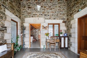 Un interior de paredes de piedra con un escritorio de madera, una silla y una alfombra estampada.