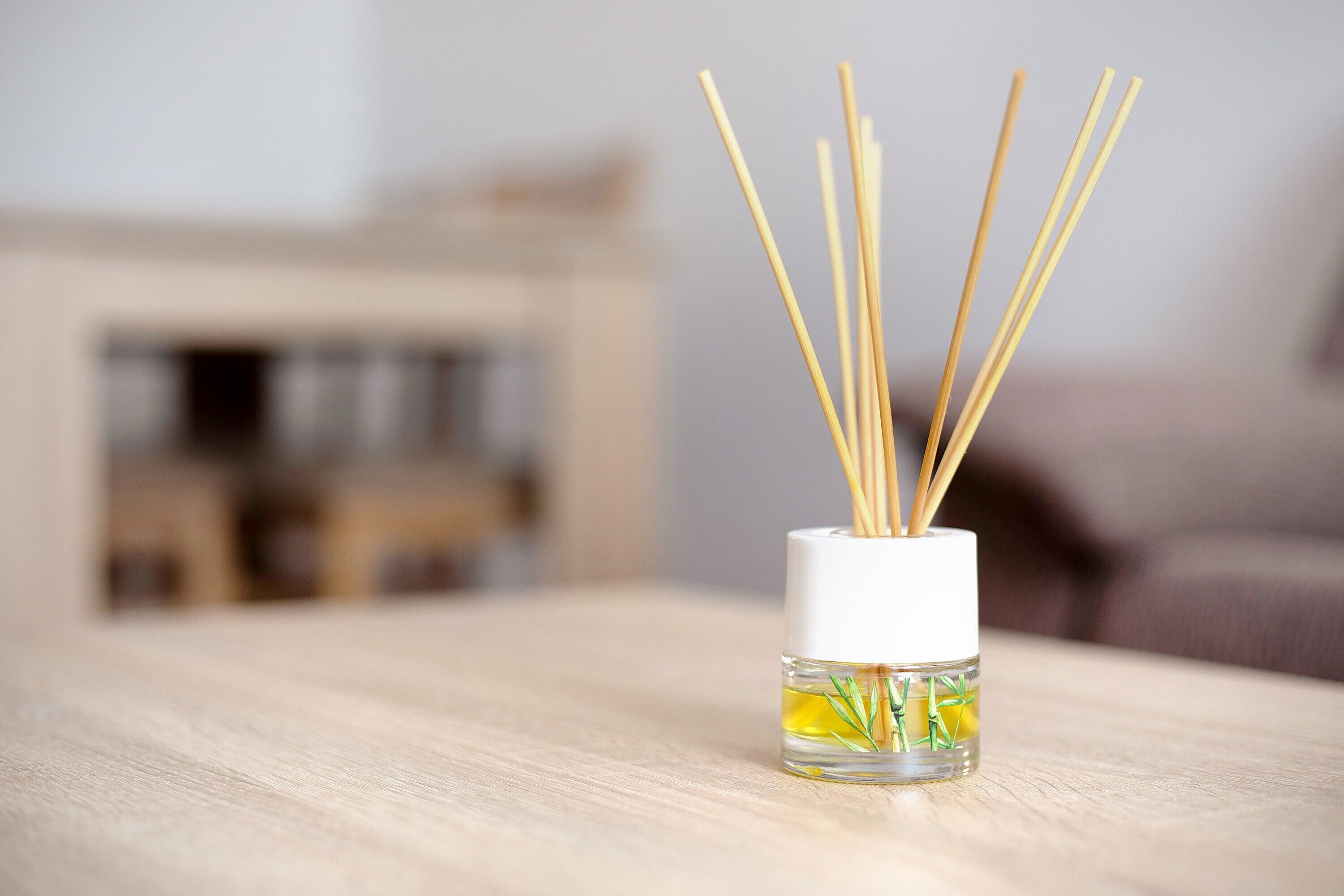 A small glass container with reed diffusers on a wooden surface.