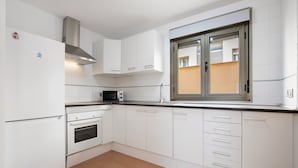 Eine moderne Küche mit weißen Schränken, einer eingebauten Mikrowelle, einer Edelstahl-Dunstabzugshaube und einem Fenster mit Jalousien.