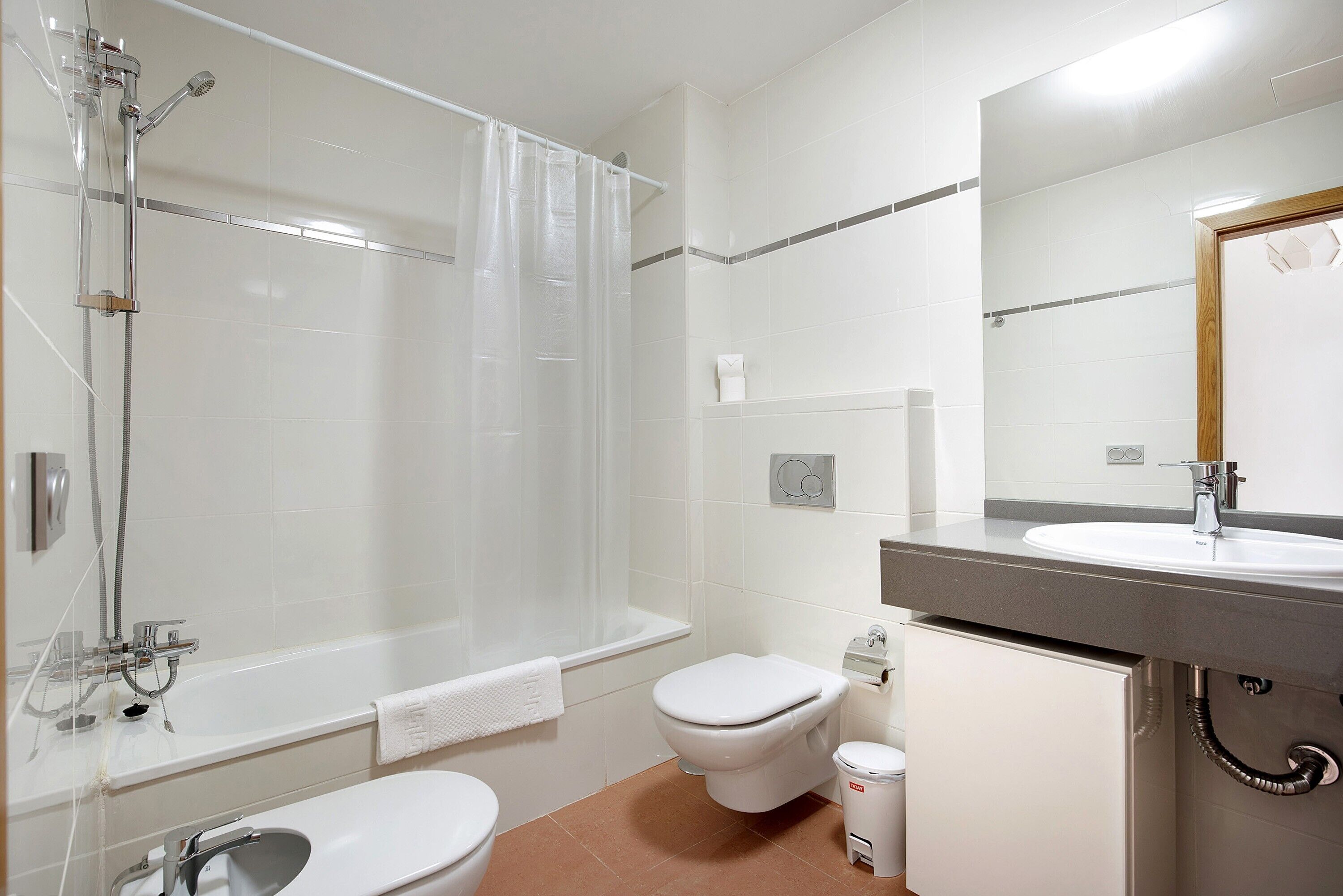 Een moderne badkamer met een bad, toilet, wastafel en douche.