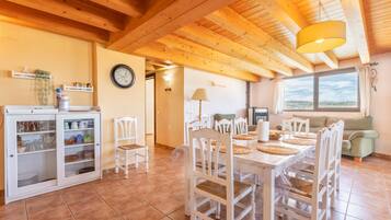 A dining area with a wooden table and chairs, a cabinet with dishes, and a clock on the wall.