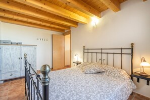 Une chambre à coucher avec un lit, des poutres en bois au plafond, une armoire et une table de chevet avec une lampe.