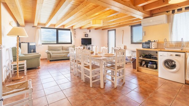 A spacious living area with a dining table, chairs, a sofa, a television, and a washing machine. - Farmhouse 'El Refugi De Rubinat' with Mountain View, Wi-Fi and Air Conditioning (Rubinat)