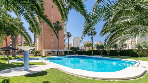 Una piscina circondata da palme e un edificio con balconi.