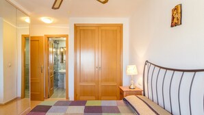 Una camera da letto con un letto, un comodino, una lampada, un'armadio in legno e uno specchio.