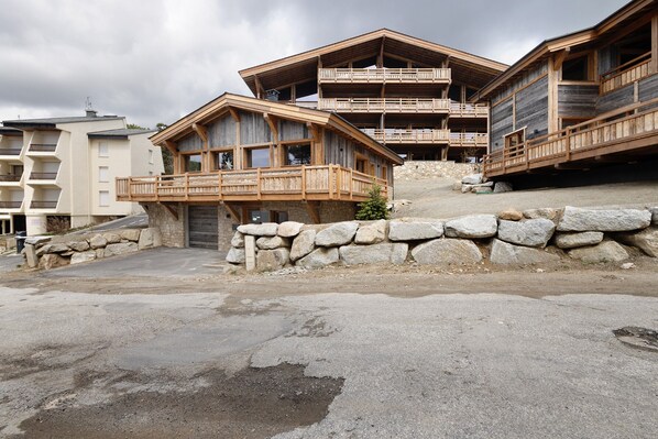 A wooden chalet with balconies, stone walls, and a paved ground. - Chalet 'Nid Des Écureuils' with Mountain View, Private Terrace and Wi-Fi (Font-Romeu-Odeillo-Via)
